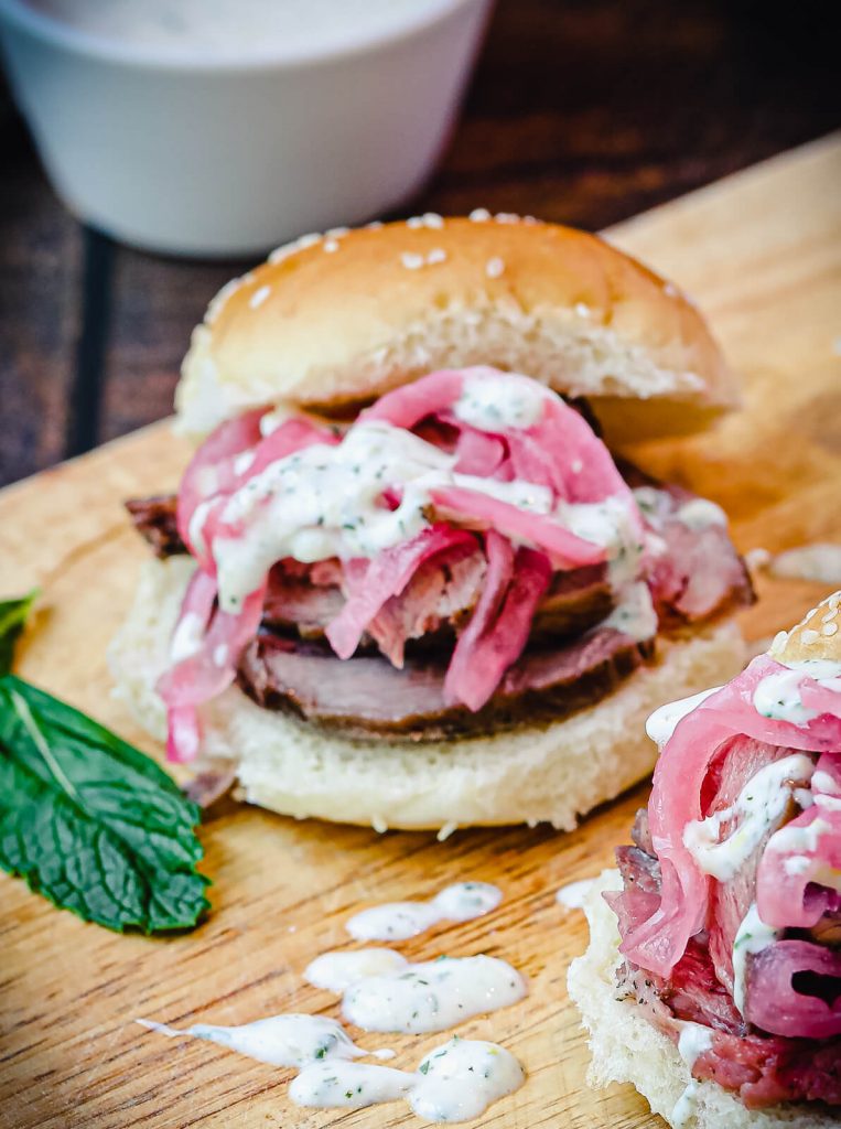 lamb slider on cutting board with sauce spilled next to it