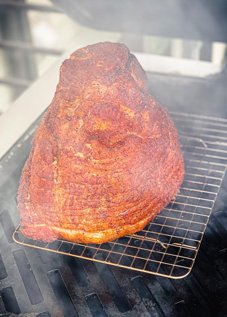 seasoned ham on a grill with smoke