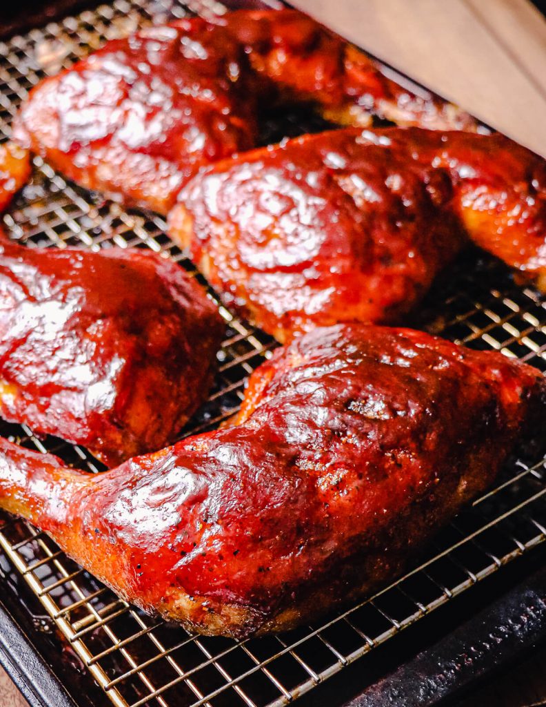 chicken quarters with bbq sauce on a cooling rack