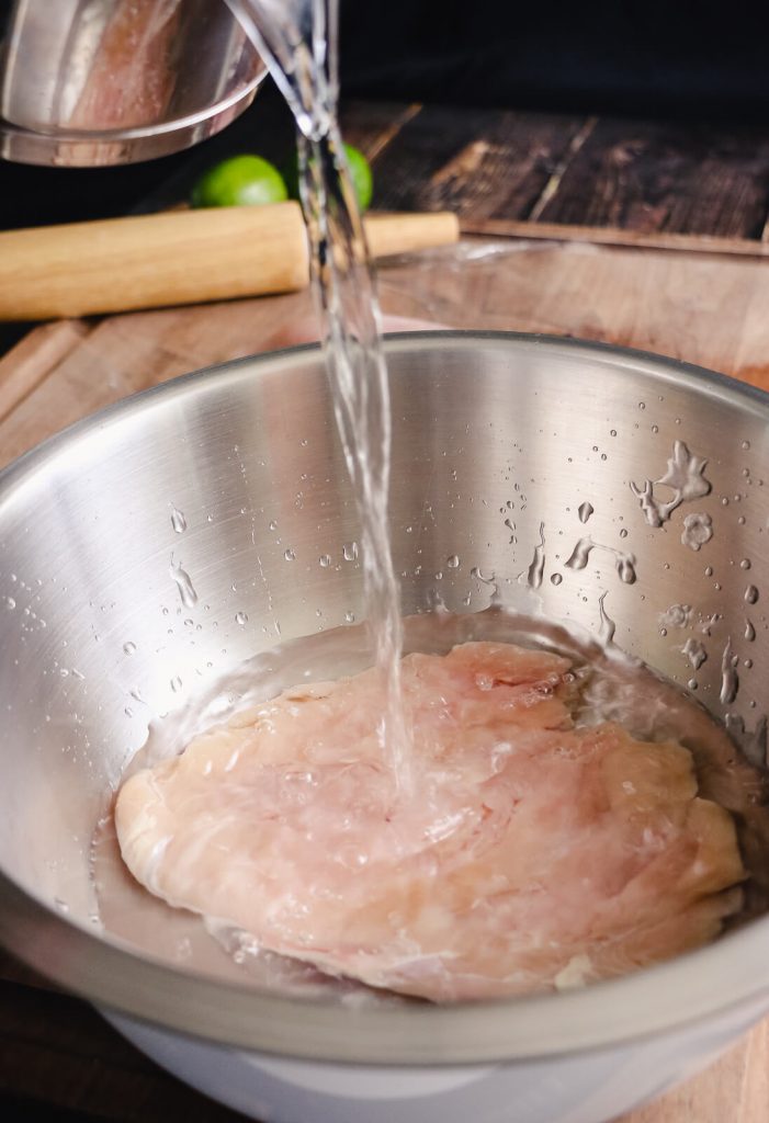 brine being added to chicken in a bowl