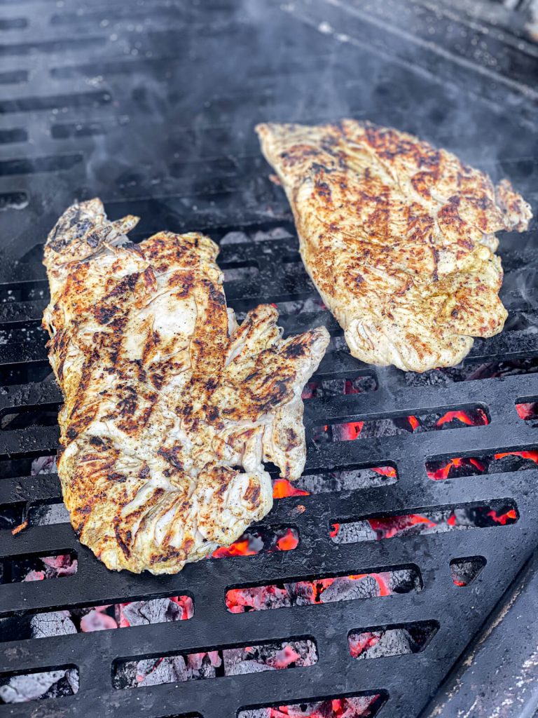 chicken breast being grilled over charcoal