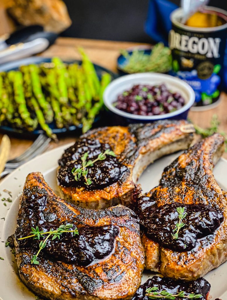 blueberry chipotle pork chops on a plate with asparagus