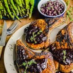 grilled pork chops with blueberry chipotle sauce on a plate with asparagus