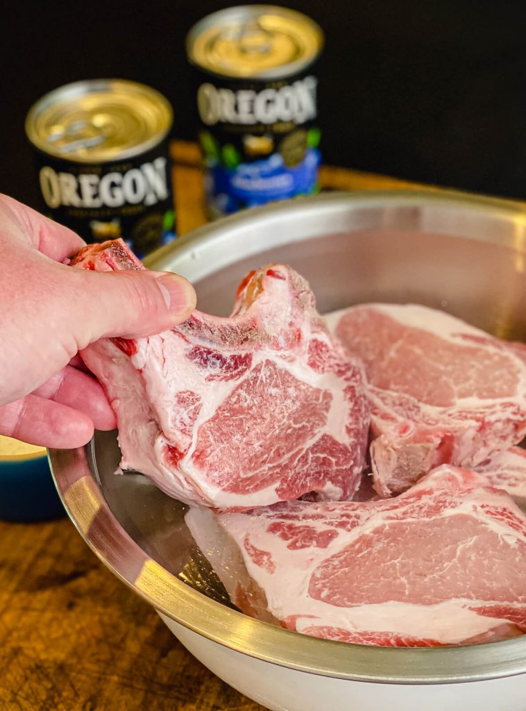 placing a pork chop into a brine for grilled pork chops with blueberry chipotle sauce