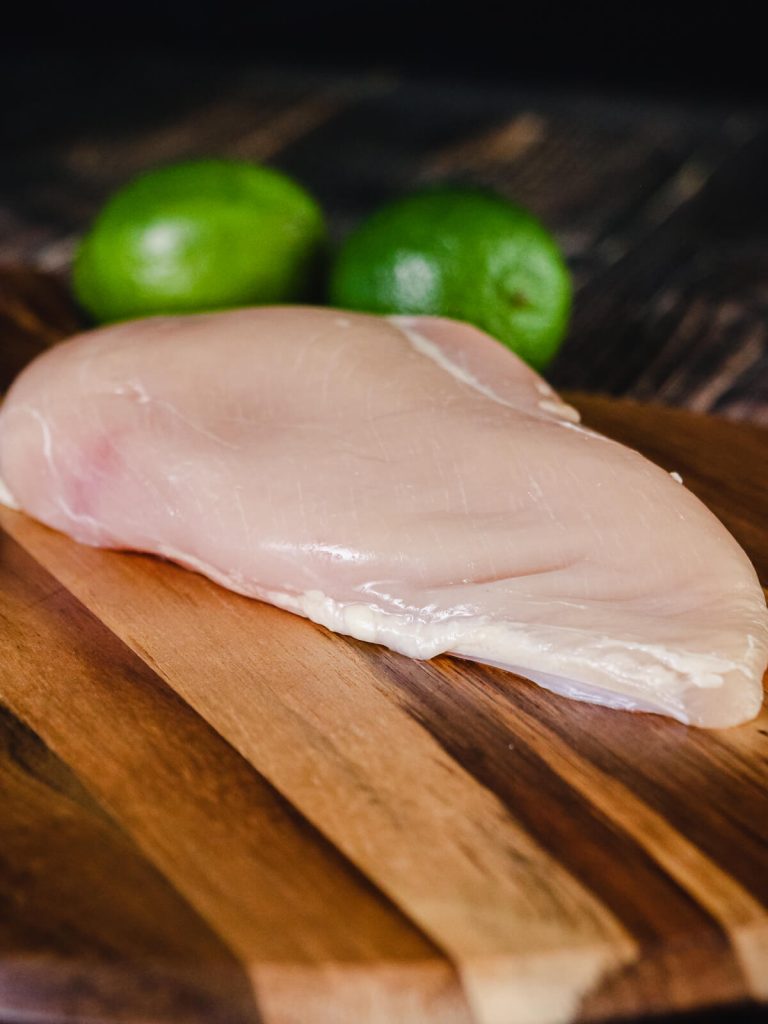 raw chicken breast on wooden cutting board