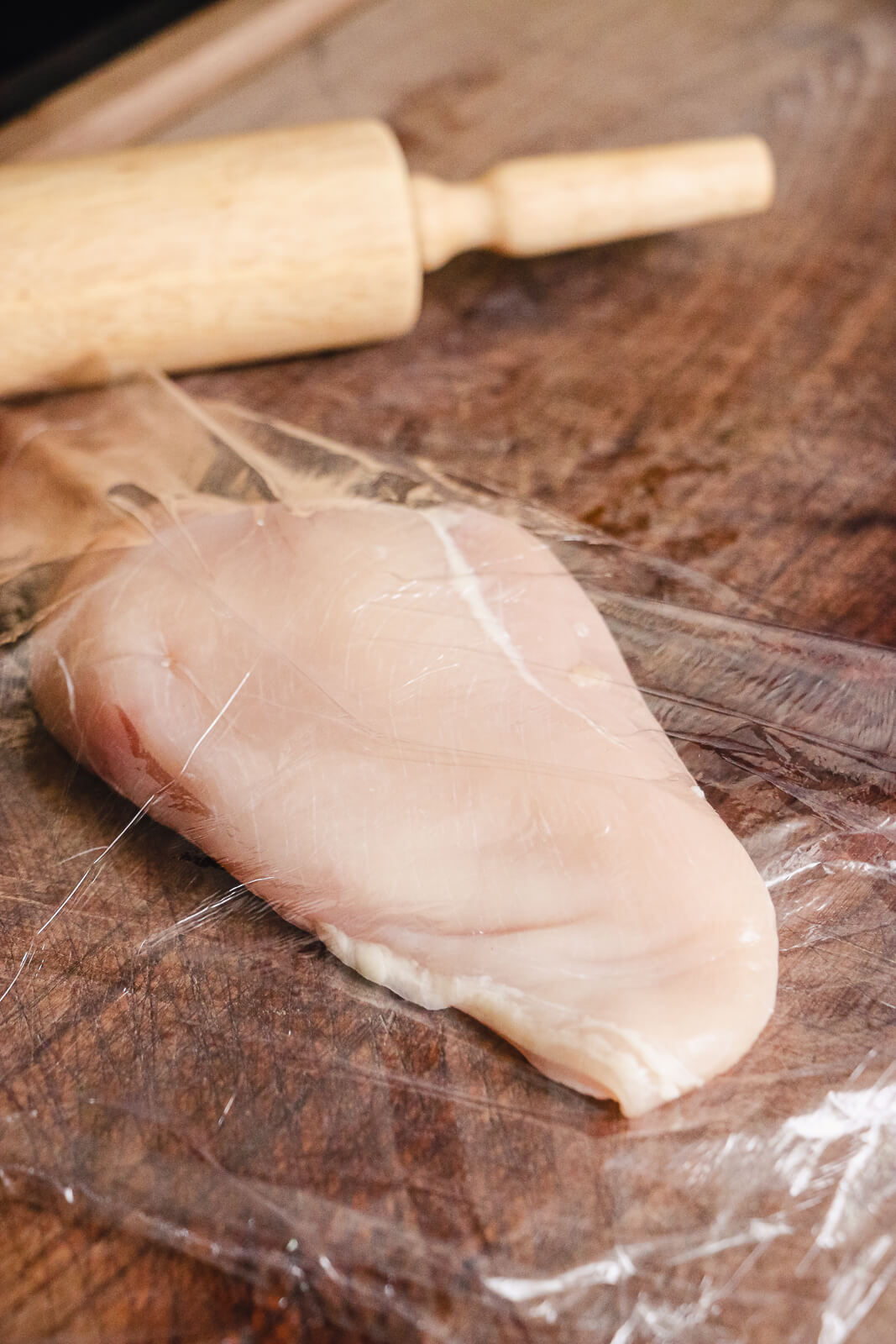 raw chicken breast on plastic wrap