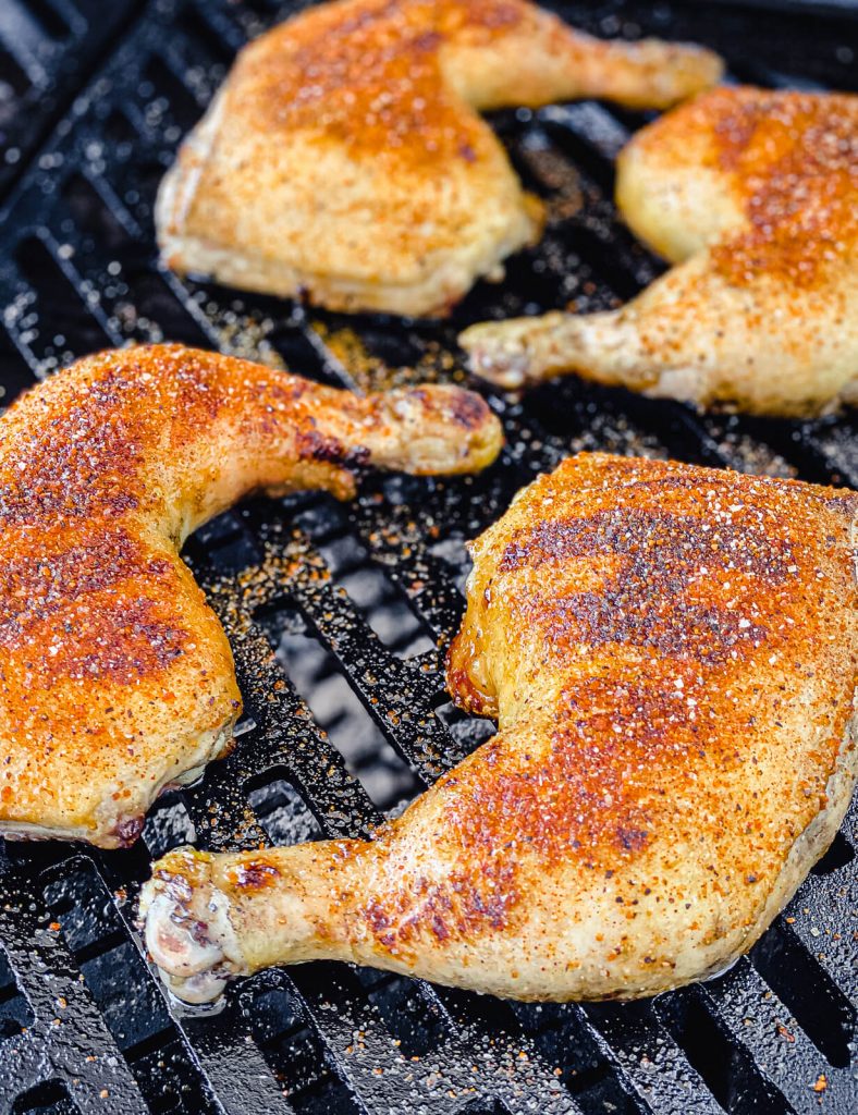 grilled chicken quarters with seasoning on the grill
