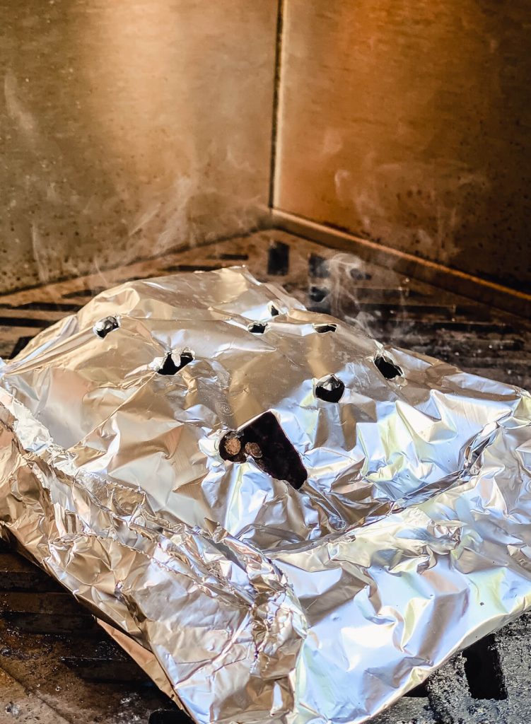 aluminum foil packet with smoke coming out of it from wood pellets