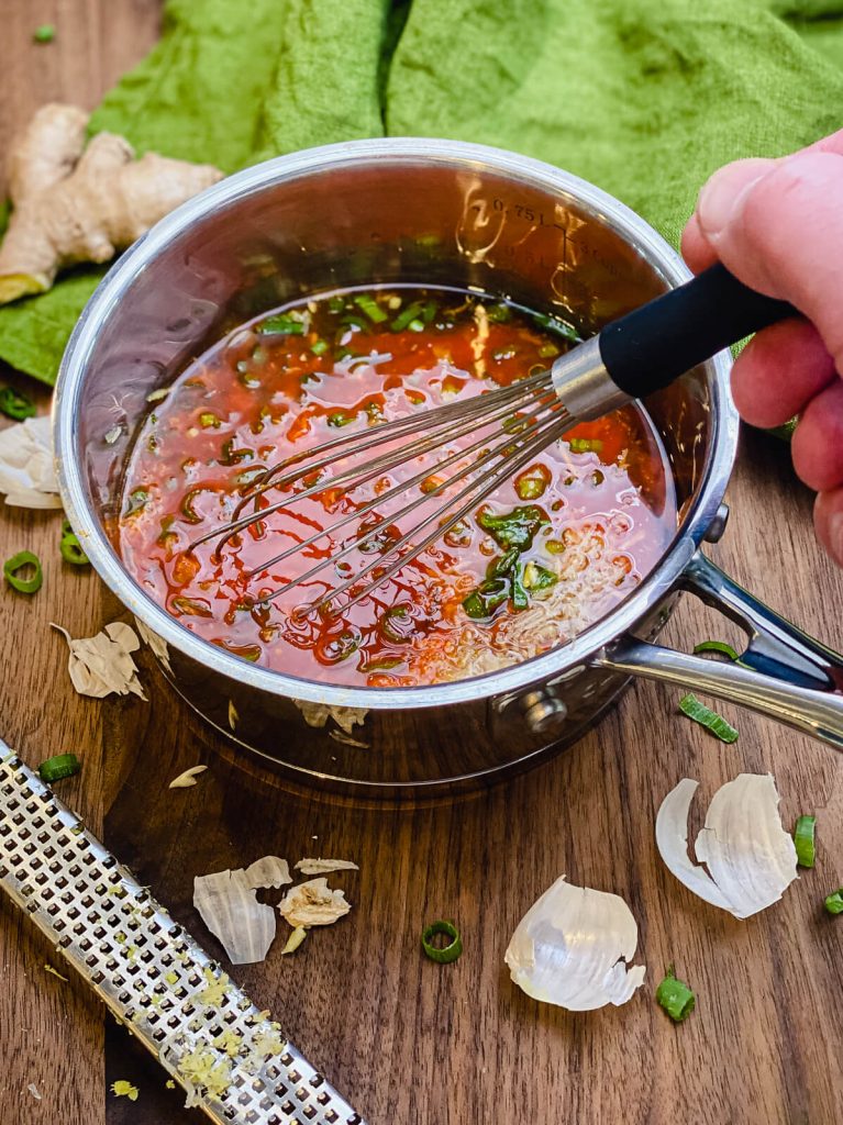 Ingredients for honey sriracha sauce being whisked together