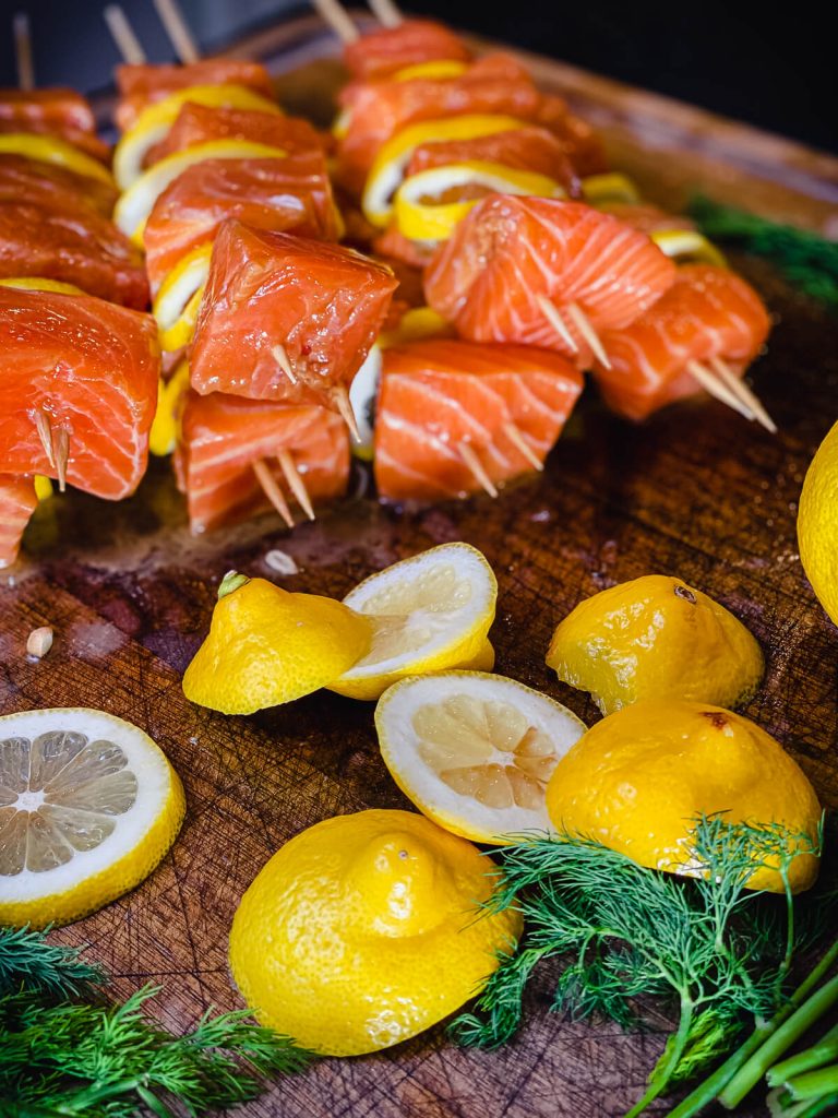 salmon kabobs on a cutting board with sliced lemons