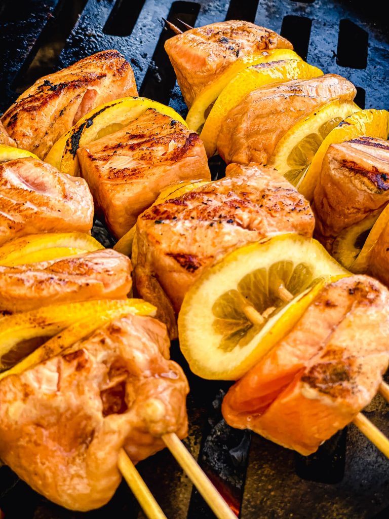 salmon kabobs being grilled over charcoal