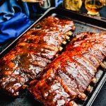 bbq ribs cooked on a gas grill sitting on a baking sheet