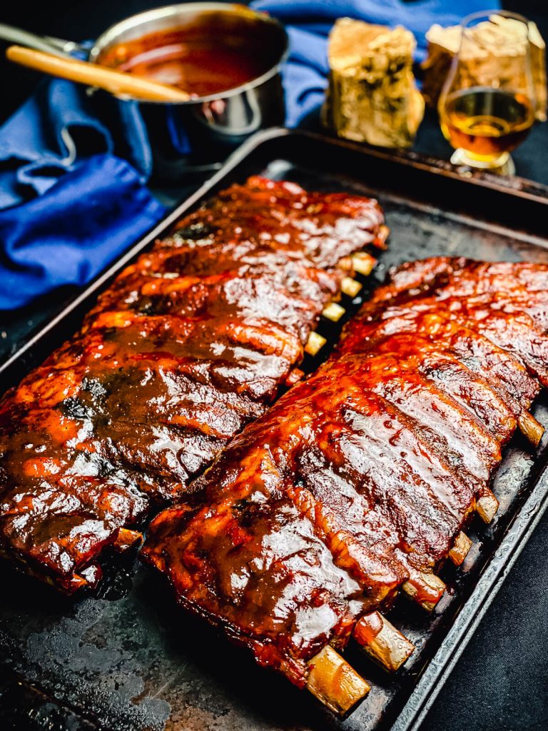 bbq ribs cooked on a gas grill sitting on a baking sheet