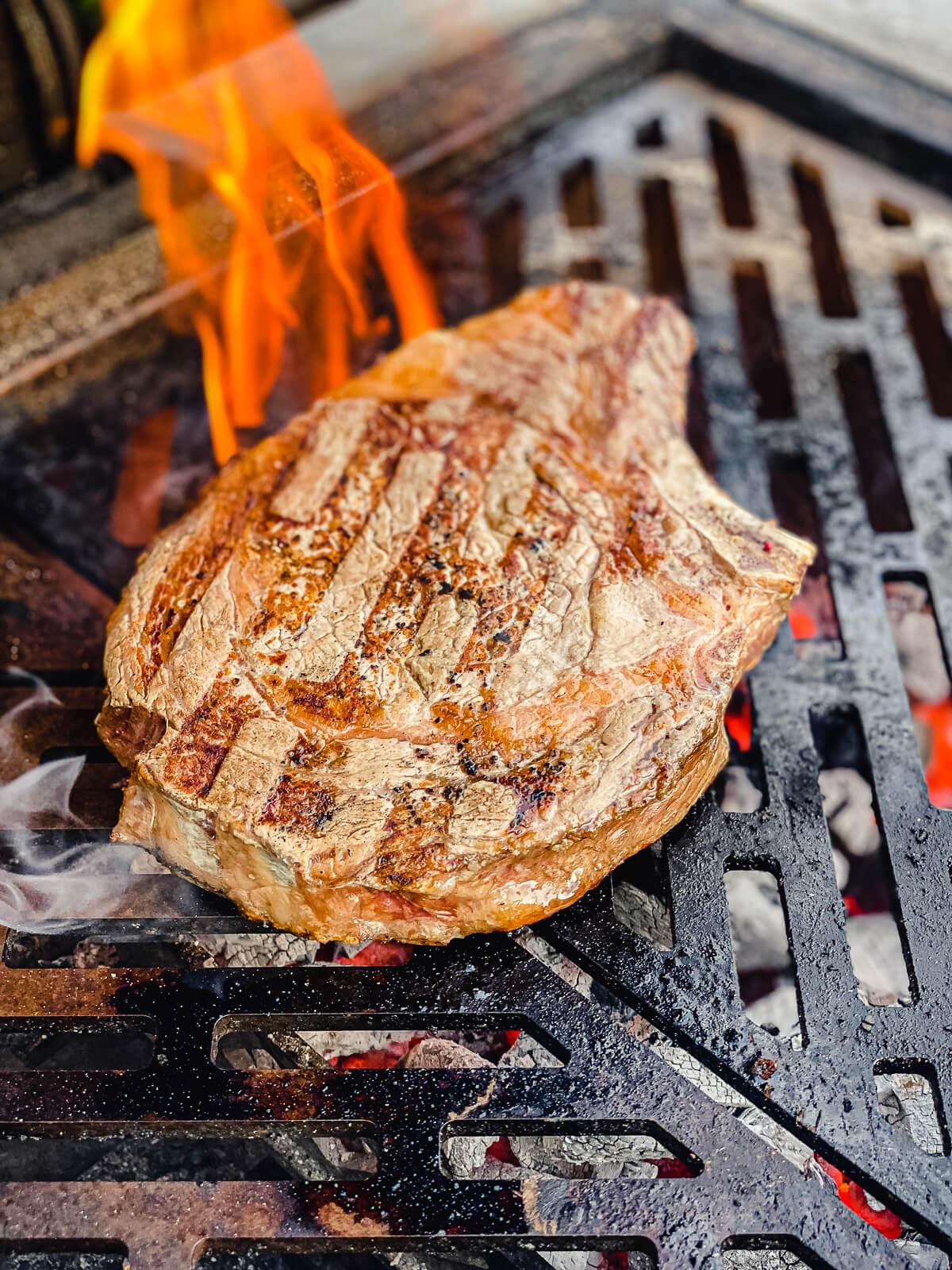 ribeye steak on grill grates with flames