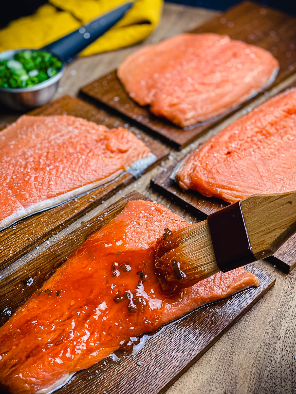cedar plank salmon with honey sriracha sauce being applied with a basting brush