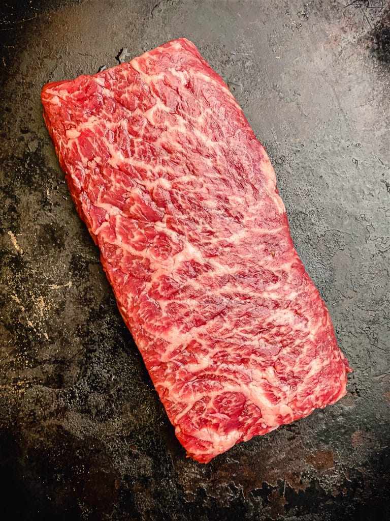boston strip steak on a black tray