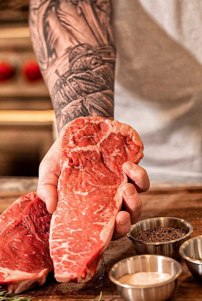 Holding a New York strip steak near a cutting board