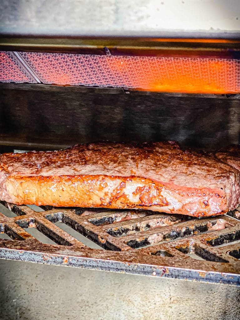 strip steak being cooked on the kalamazoo gas grill head