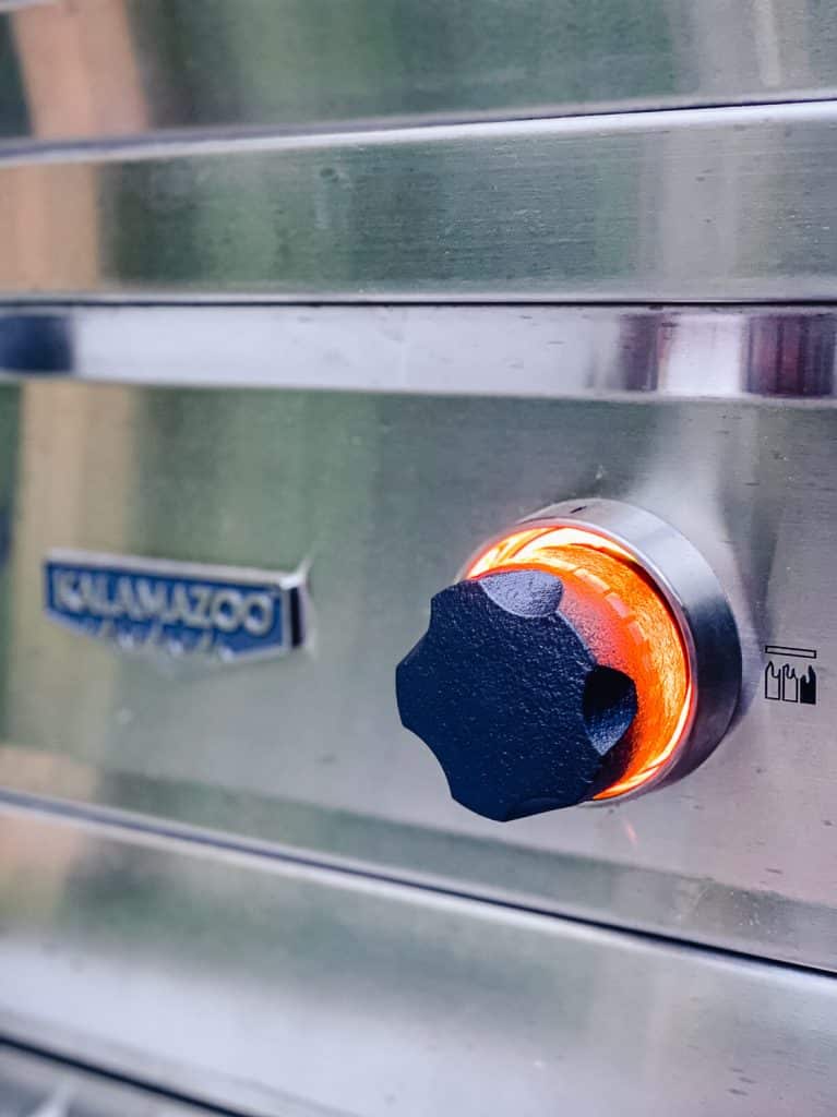 Kalamazoo gas grill head gas control knob backlit in orange indicating the burner is lit.