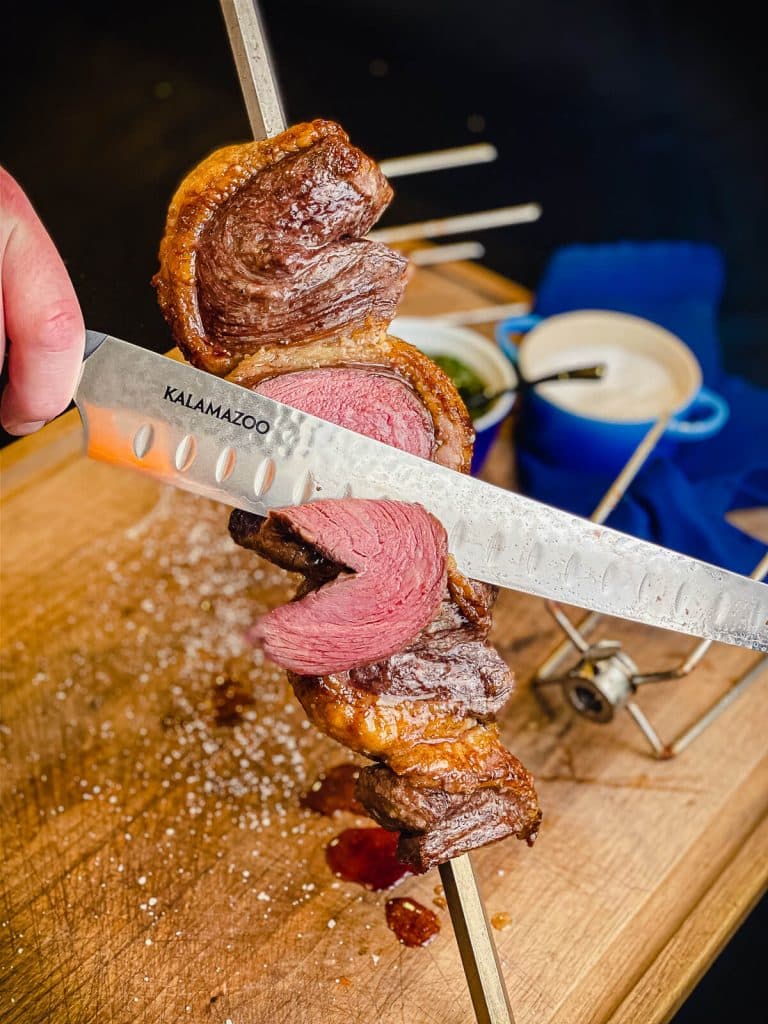 slicing a piece of picanha from the spit