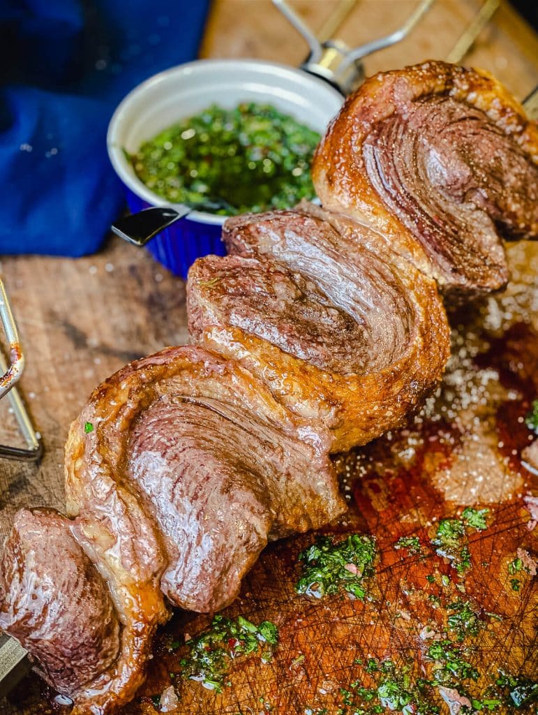 roasted picanha on a cutting board with chimichurri