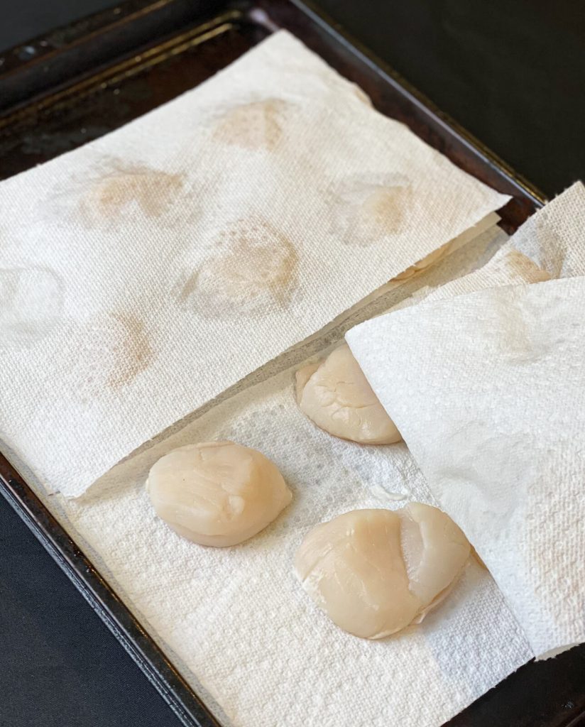 raw scallops being dried on a paper towel