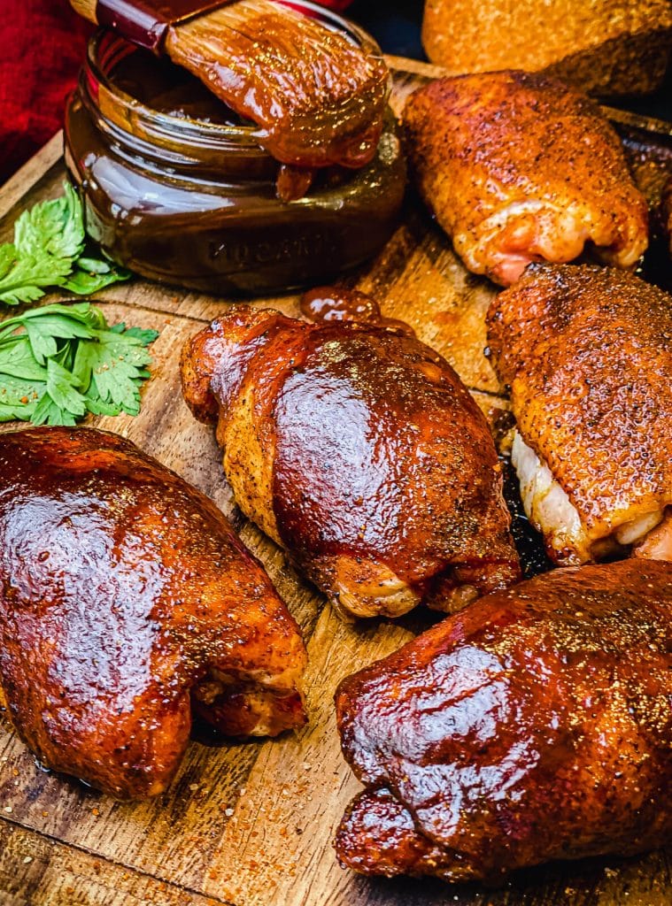 smoked chicken thighs with a jar of bbq sauce