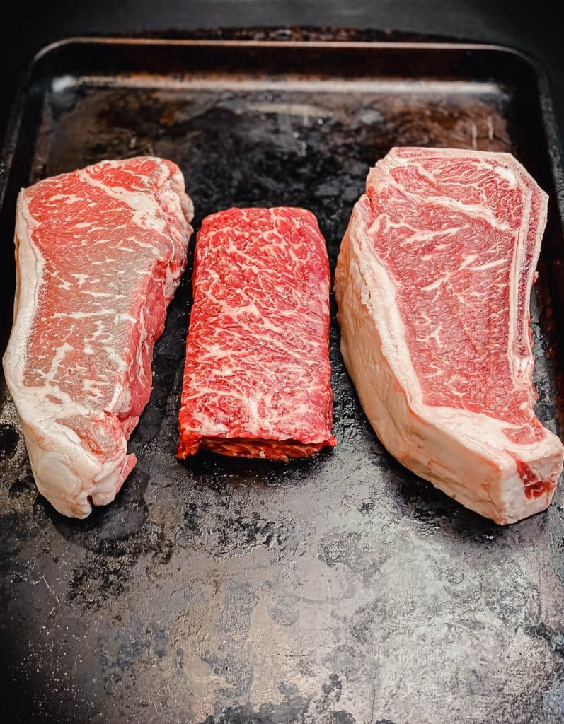 New York strip steak, Kansas City strip steak, and Boston strip steak on a tray