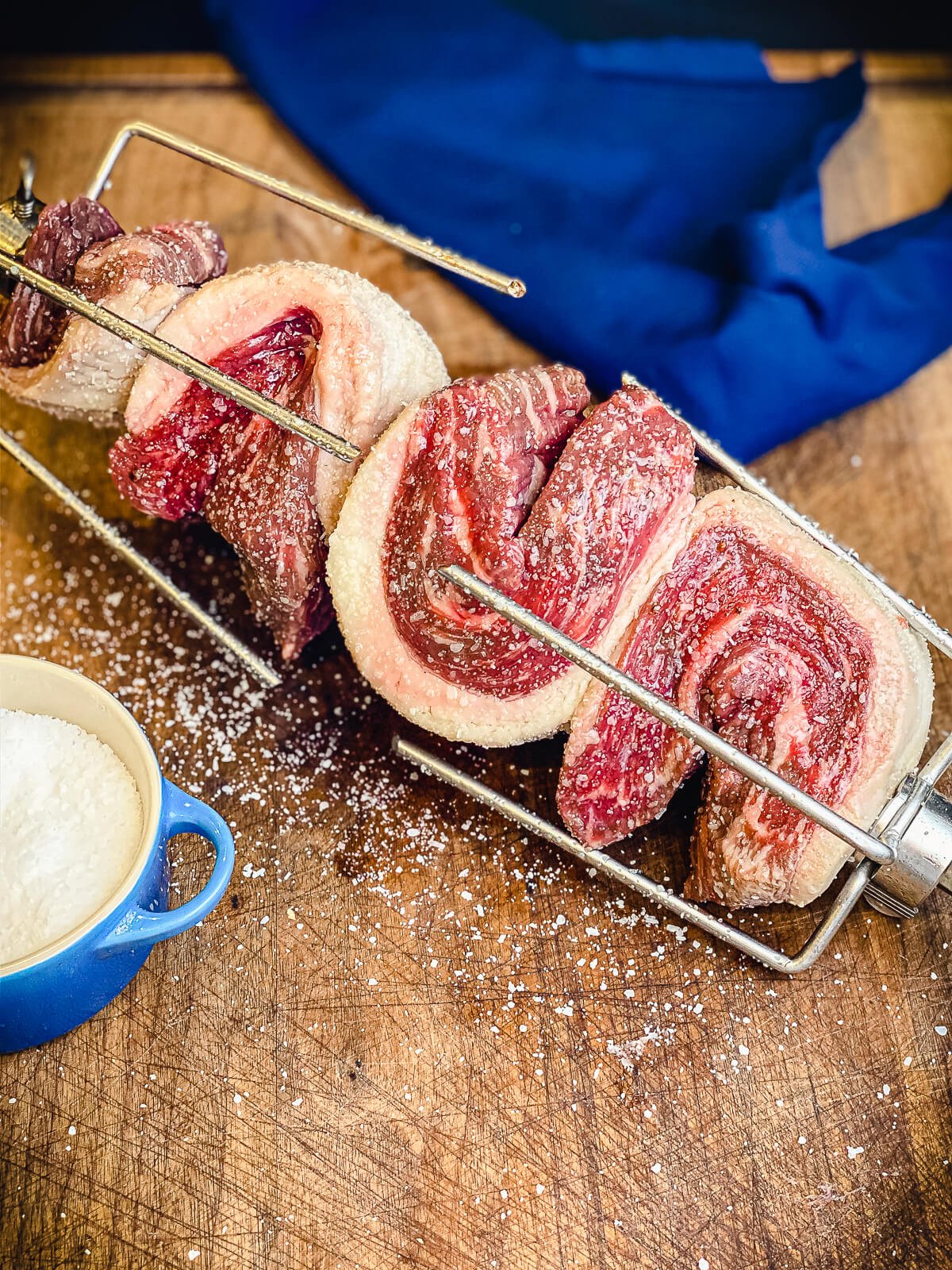 picanha secured to a rotisserie spit with salt