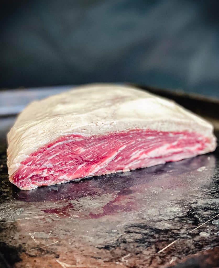 Whole uncooked picanha on black tray