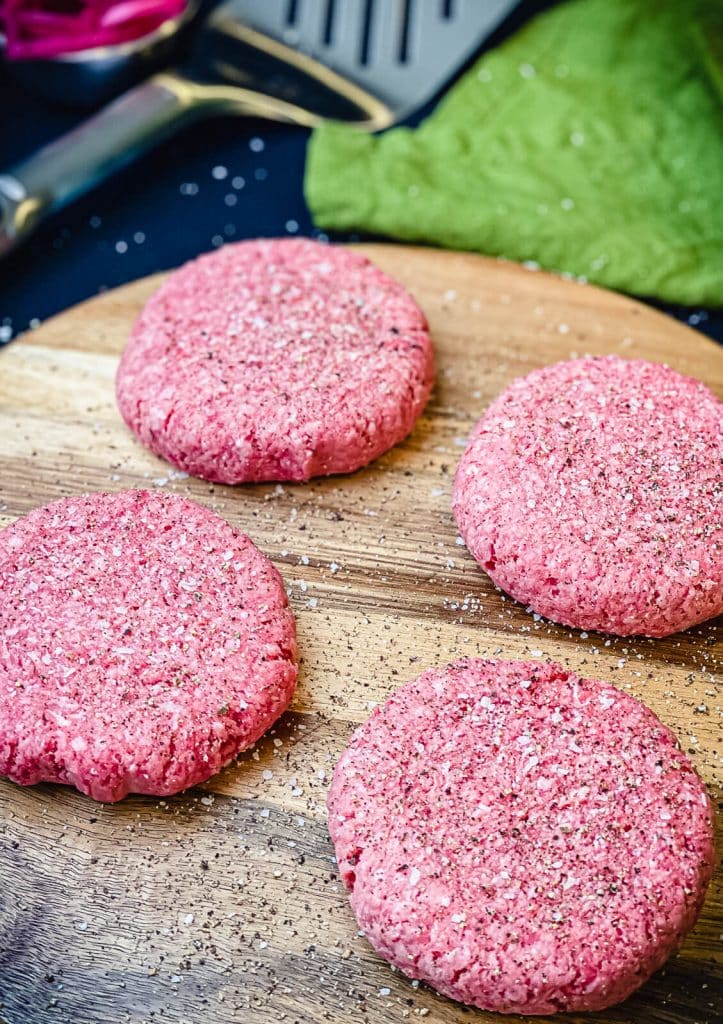 burger patties on a cutting board with green towel