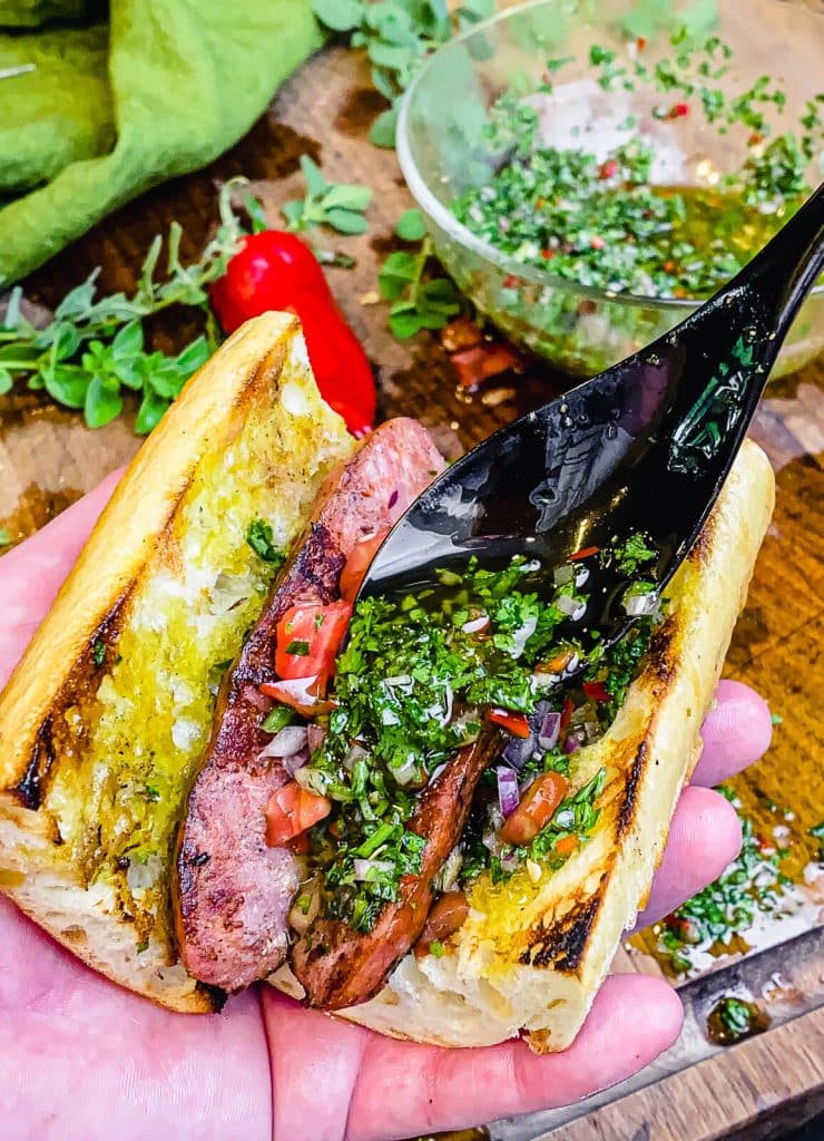 chimichurri being applied to a choripan