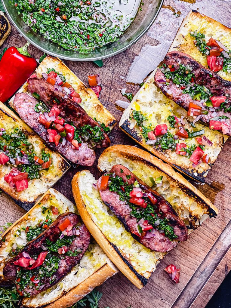 choripan on a cutting board dressed with chimichurri and salsa