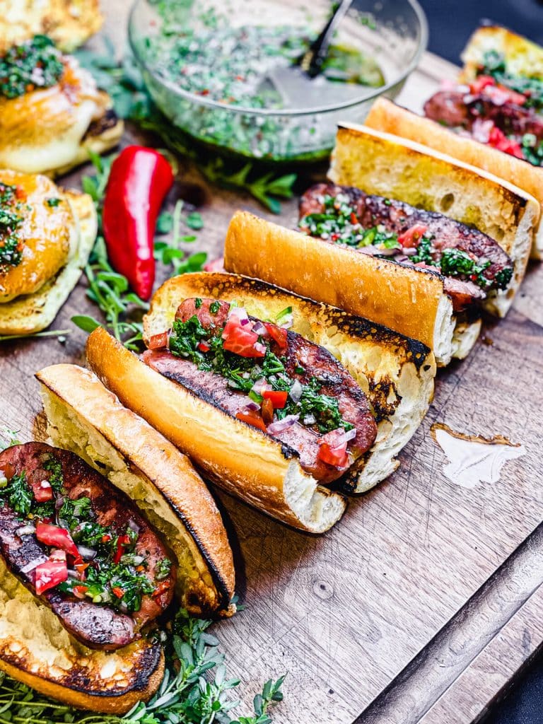 choripan sitting on a cutting board with red pepper and chimichurri