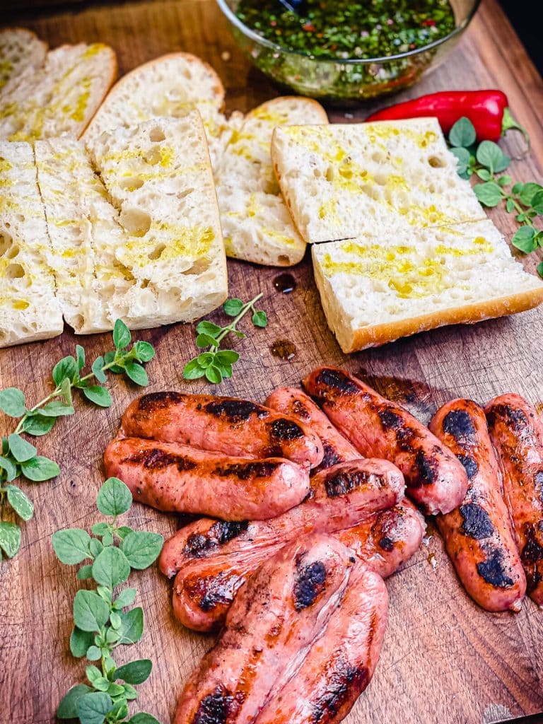 cooked chorizo and french bread on a cutting board