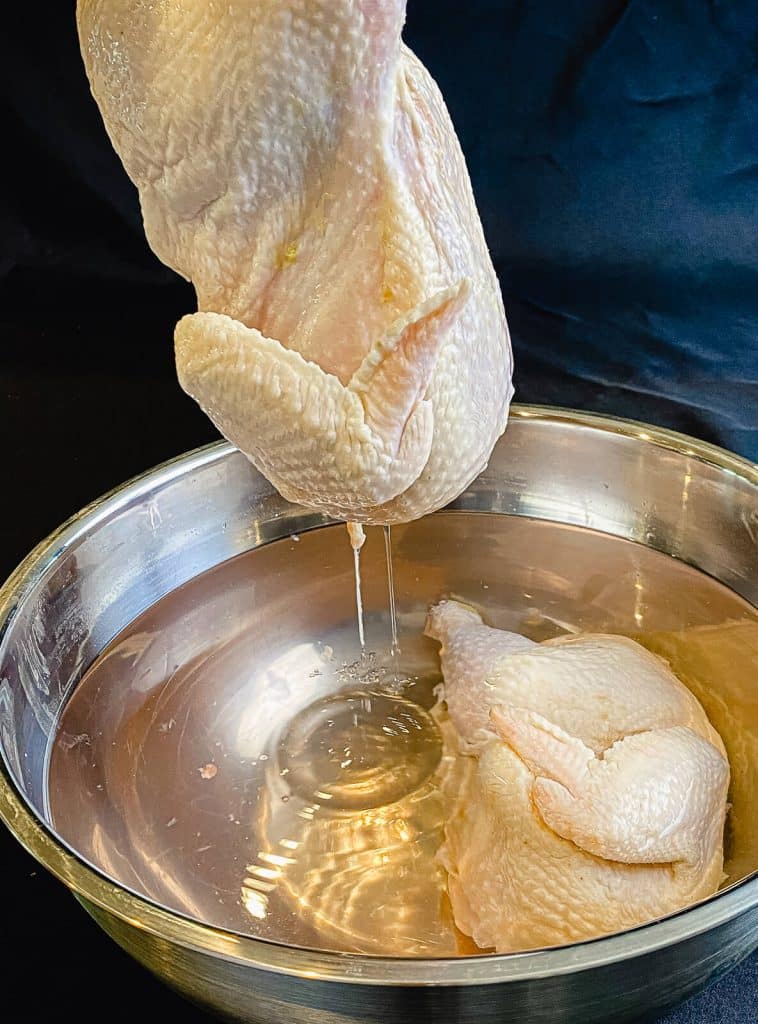 half chicken being removed from brine