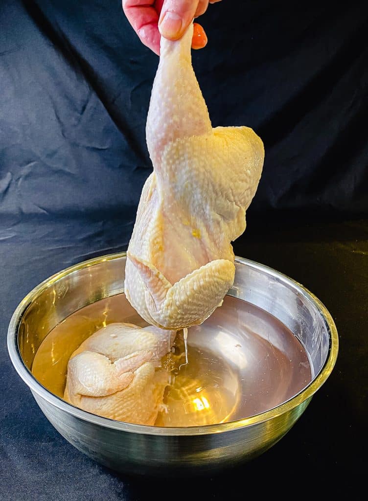 half chicken being removed from a salt water brine