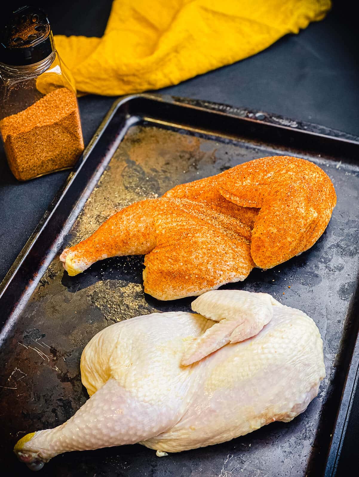 chicken halves being seasoned for the grill