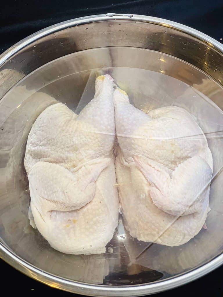chicken halves submerged in a salt water brine
