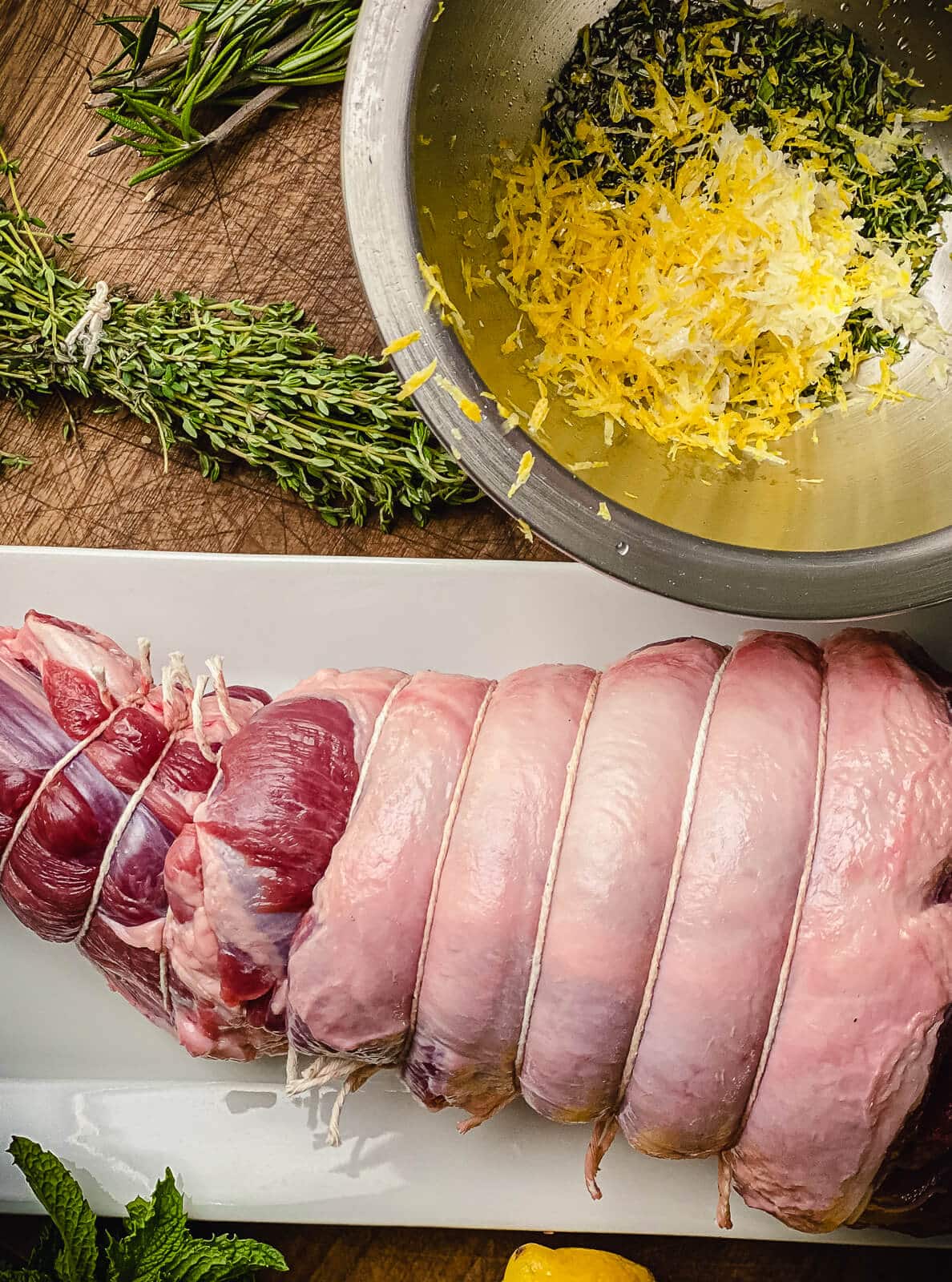 leg of lamb and herbs on a cutting board