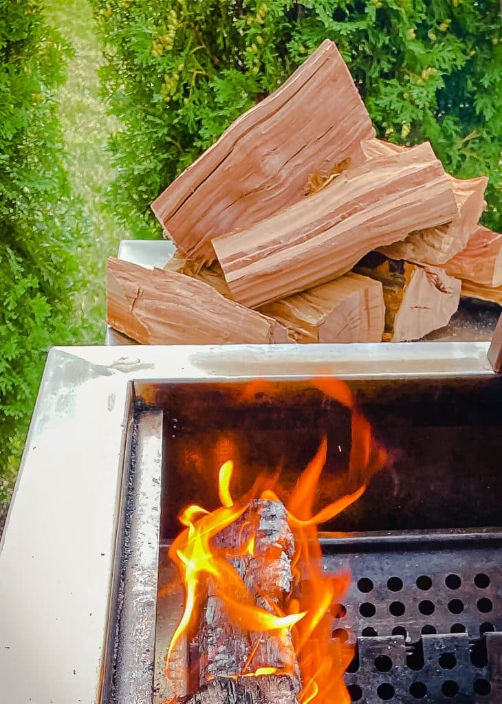 pile of oak wood for smoking meat near a grill