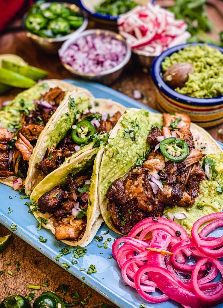 grilled pork carnitas tacos with pickled red onion on a blue platter