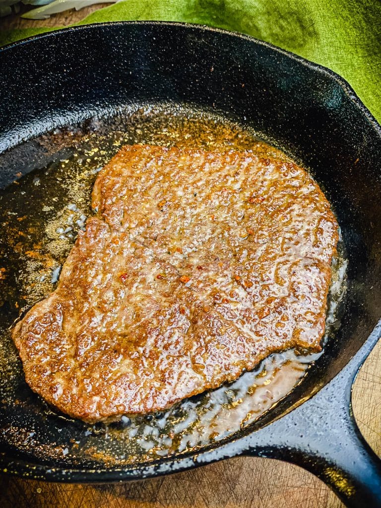 cube steak searing in cast iron pan