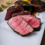 sliced sous vide filet mignon on a white plate showing it's medium rare pink center