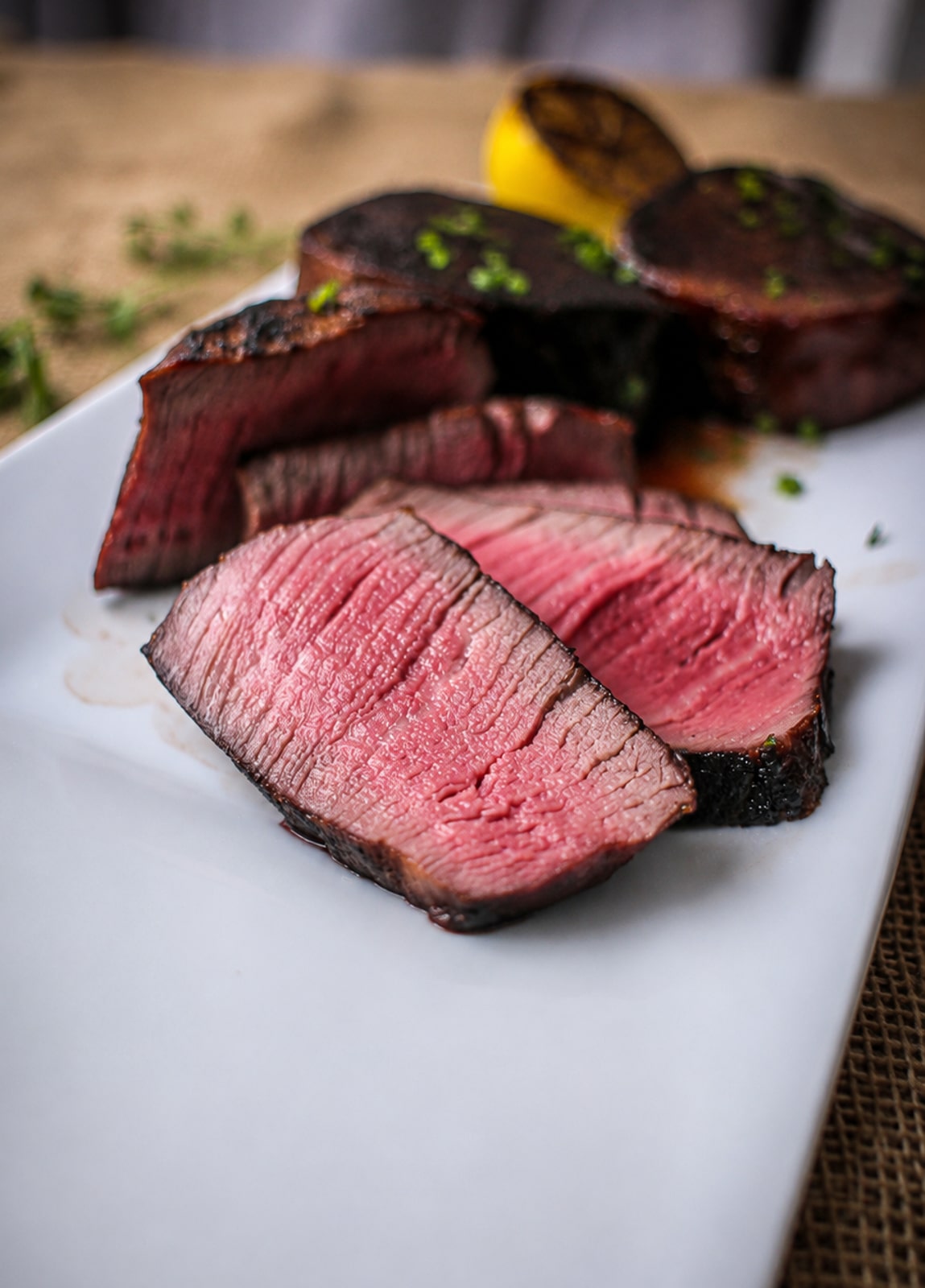sliced sous vide filet mignon on a white plate showing it's medium rare pink center