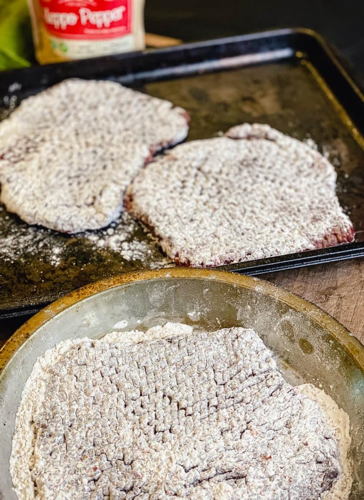 seasoned cube steaks on a baking sheet