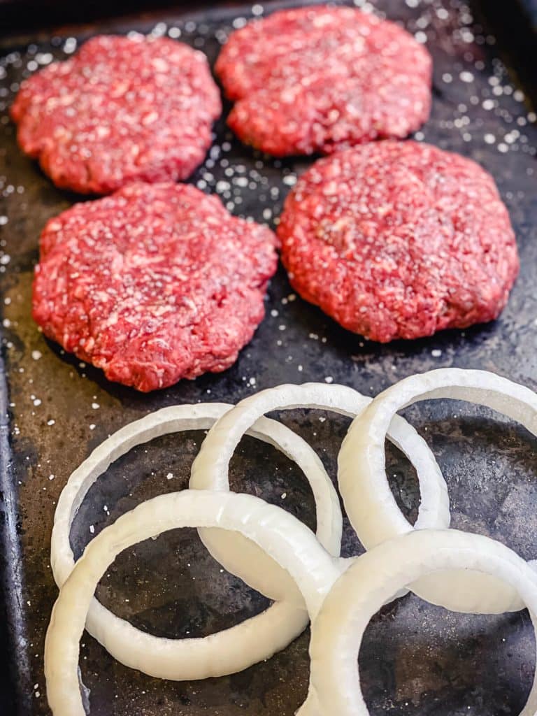 vension burger patties with onions on a platter