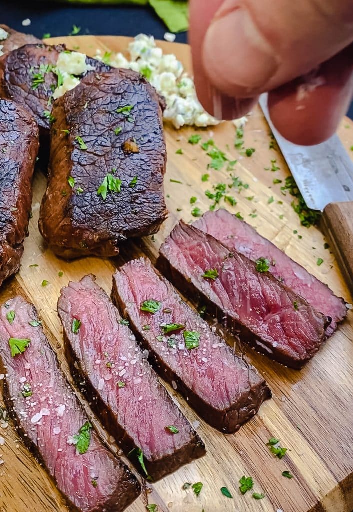 salt being added to a sliced venison steak