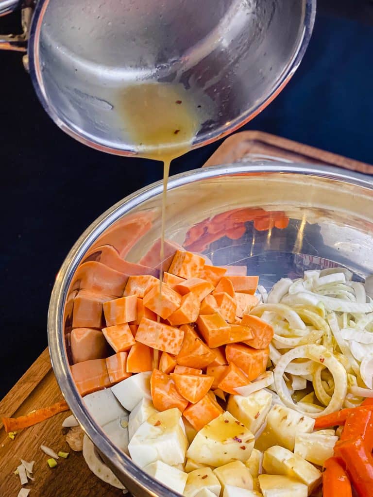 miso maple glaze being added to raw root vegetables