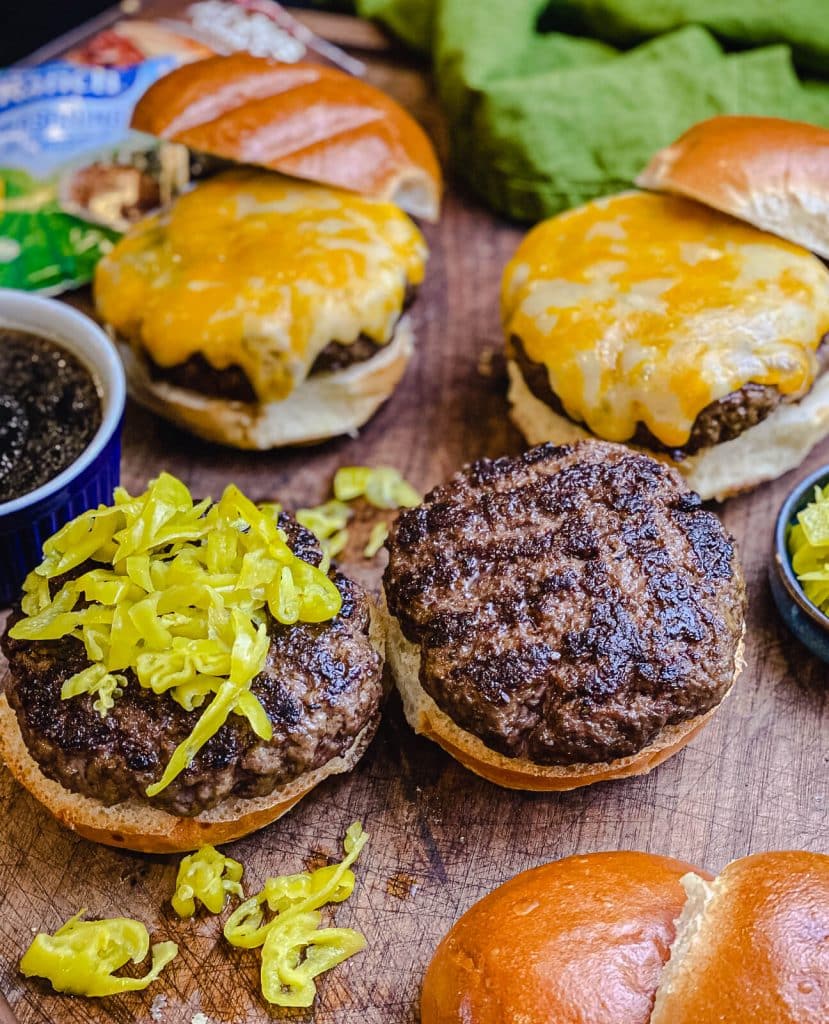 burgers setting on a wooden cutting board